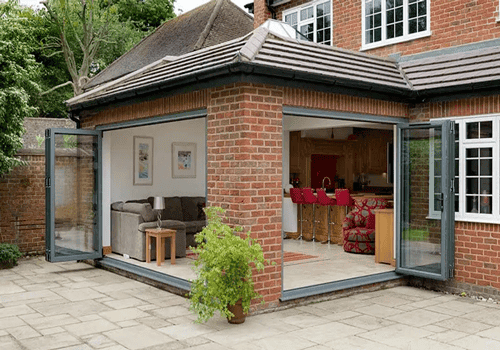 A home extension hosting a relaxing sitting area that opens out onto the back garden through wide patio windows.